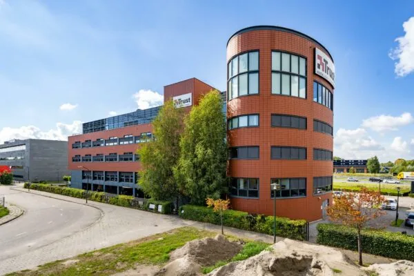 Kantoorgebouw van Trust aan de Laan van Barcelona met ronde voorkant en roodbruine gevel.